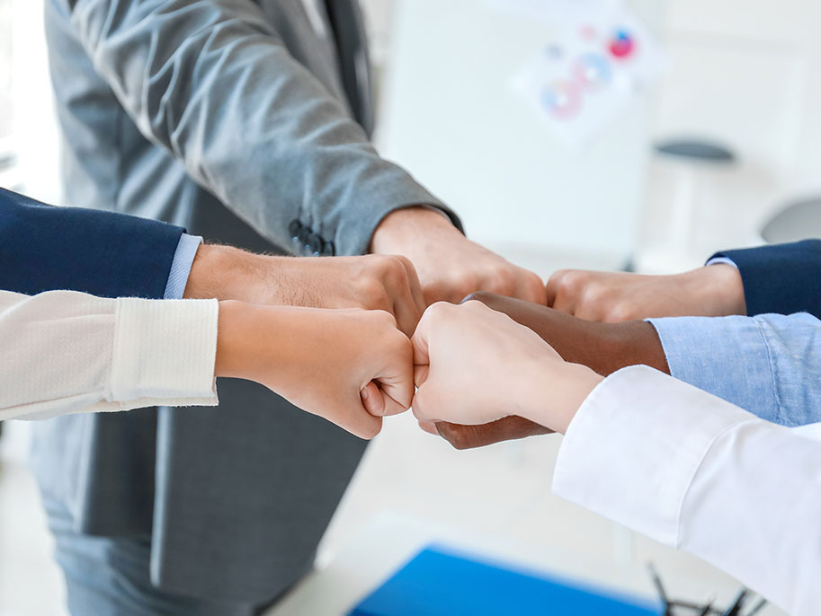 Six team members demonstrating collaboration and leadership through a group fist bump.